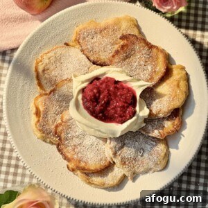 Polish Racuchy: Classic Apple Pancake Recipe You’ll Love 19 racuchy on a white plate with raspberry compote and whipped cream.