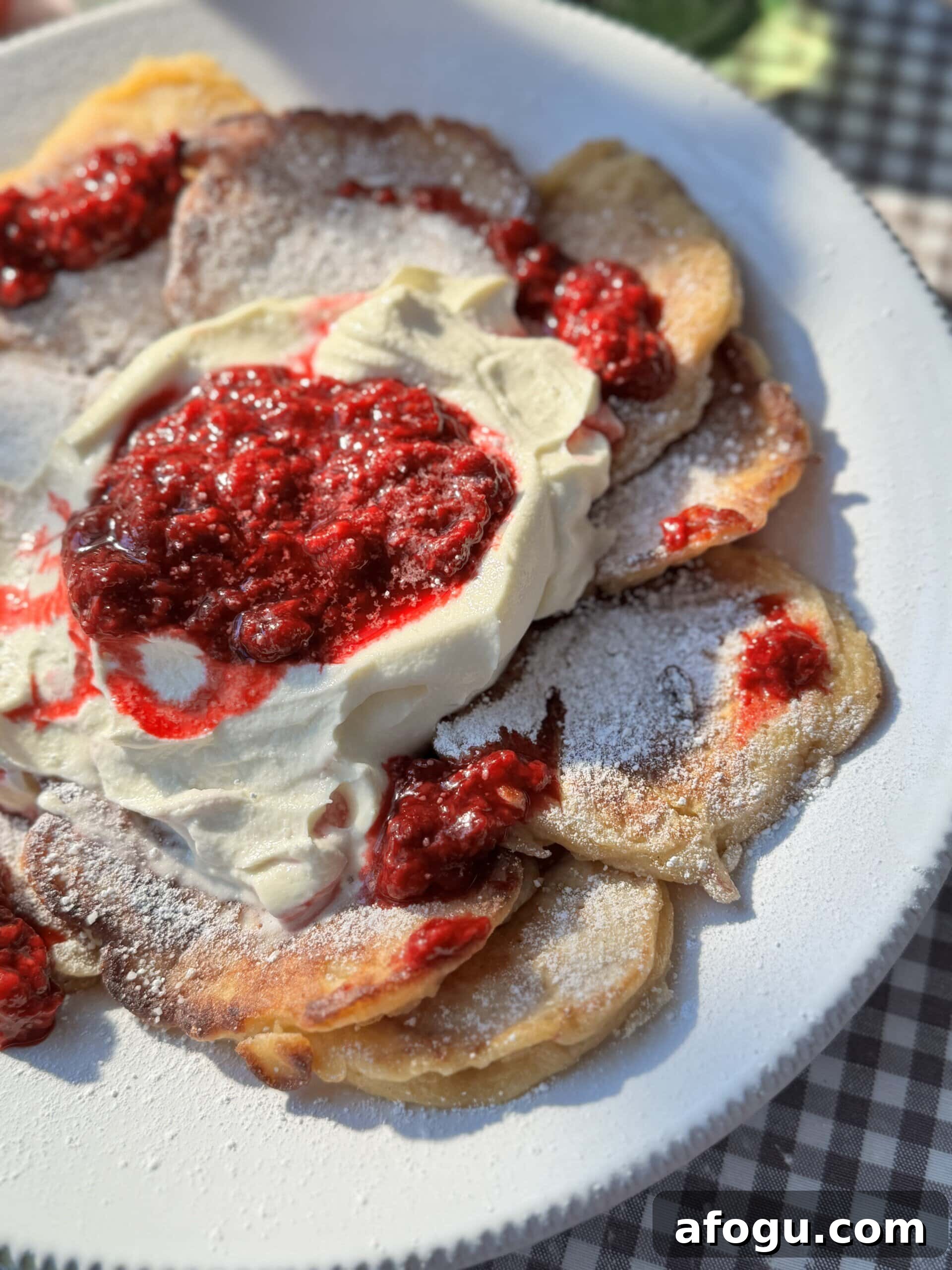 Polish Racuchy: Classic Apple Pancake Recipe You’ll Love 3 racuchy on a white plate with raspberry compote and whipped cream.