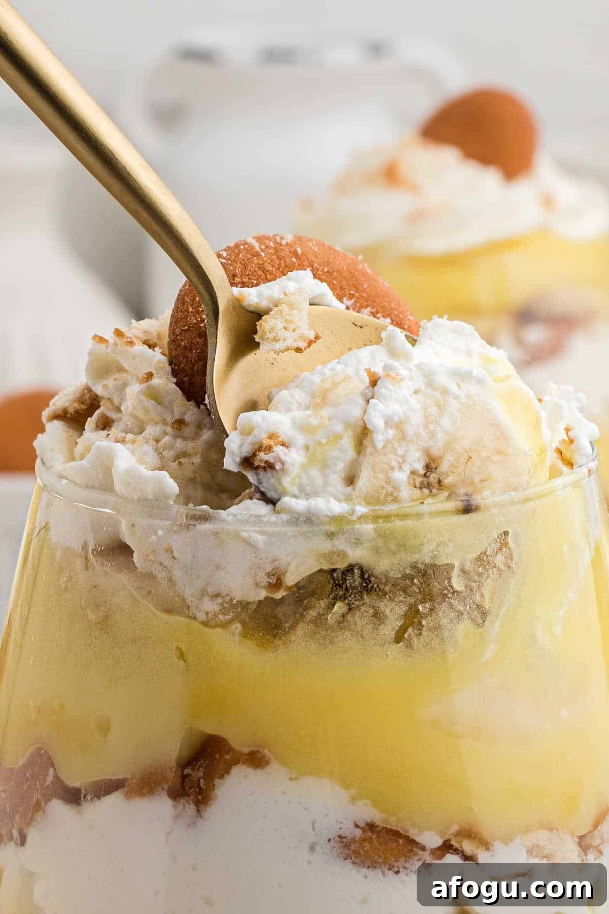 Close up of a banana pudding cup with a spoon taking some out.