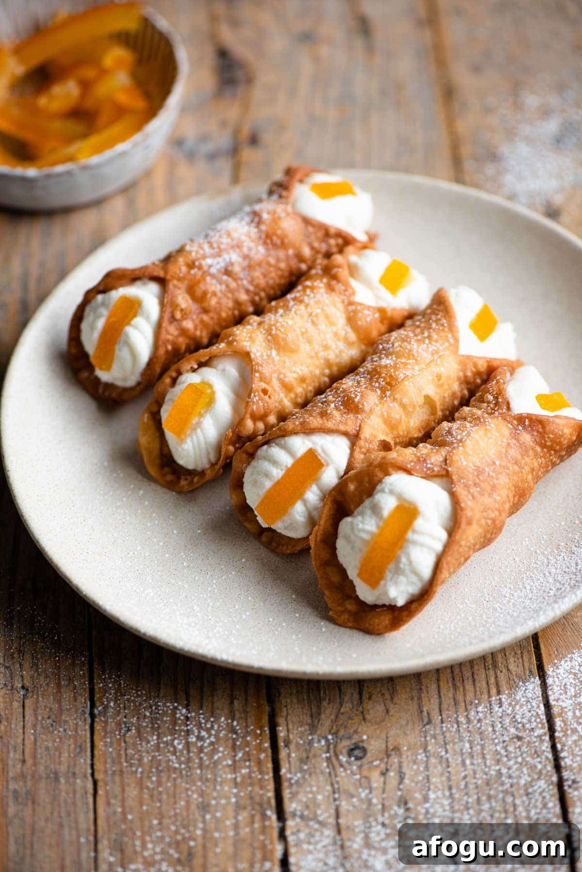 Homemade Sicilian Cannoli Recipe: Crispy Shells & Ricotta Filling 2 Four cannoli on a plate filled with ricotta and a slice of candied orange