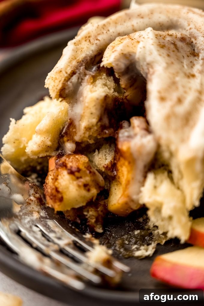 A closeup of the filling of an apple cinnamon roll on a plate with a fork.