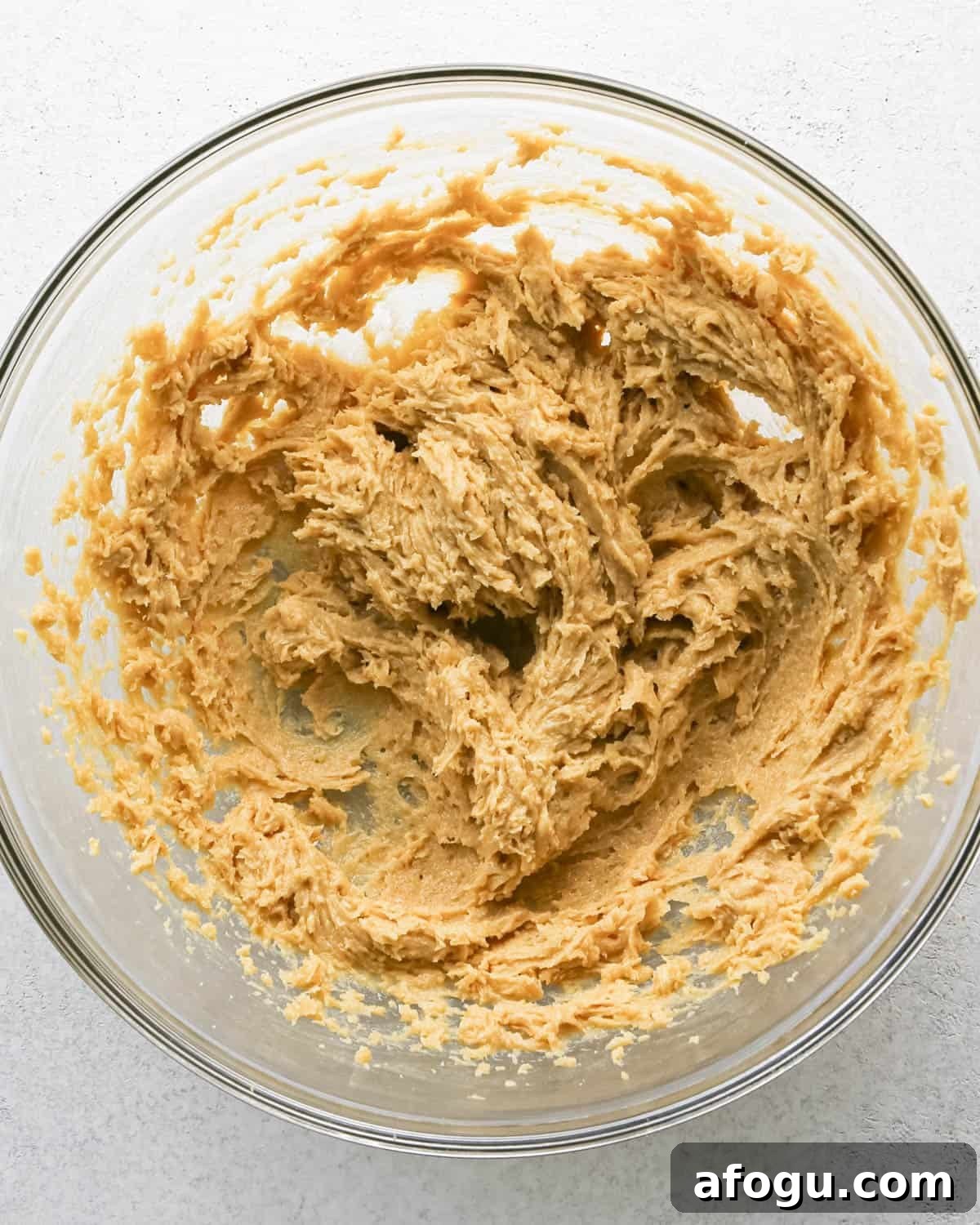 Chocolate Chip Cashew Cookies Recipe — Crunchy Homemade Treats 12 Making chocolate chip cashew cookies: overhead photo of egg, vanilla, cashew butter, butter, and sugar mixed together in a large clear mixing bowl.