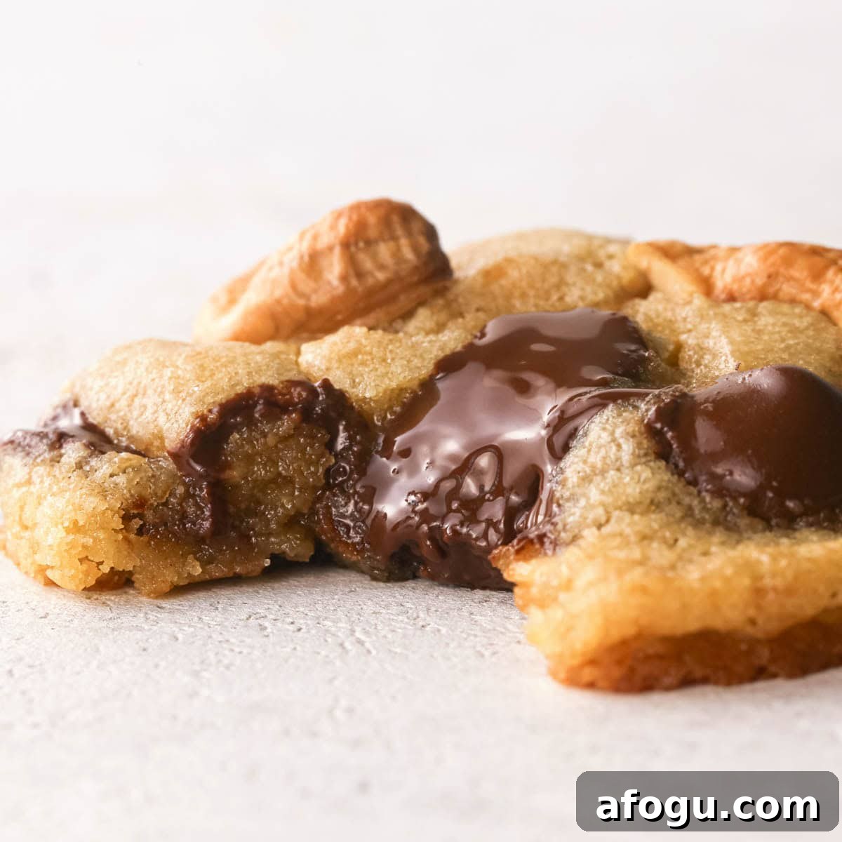 Chocolate Chip Cashew Cookies Recipe — Crunchy Homemade Treats 21 Up-close photo of a chocolate chip cashew cookie with a bite taken out of it to show the melty chocolate, the crispy outside, and the chewy, perfectly gooey inside of the cookie.