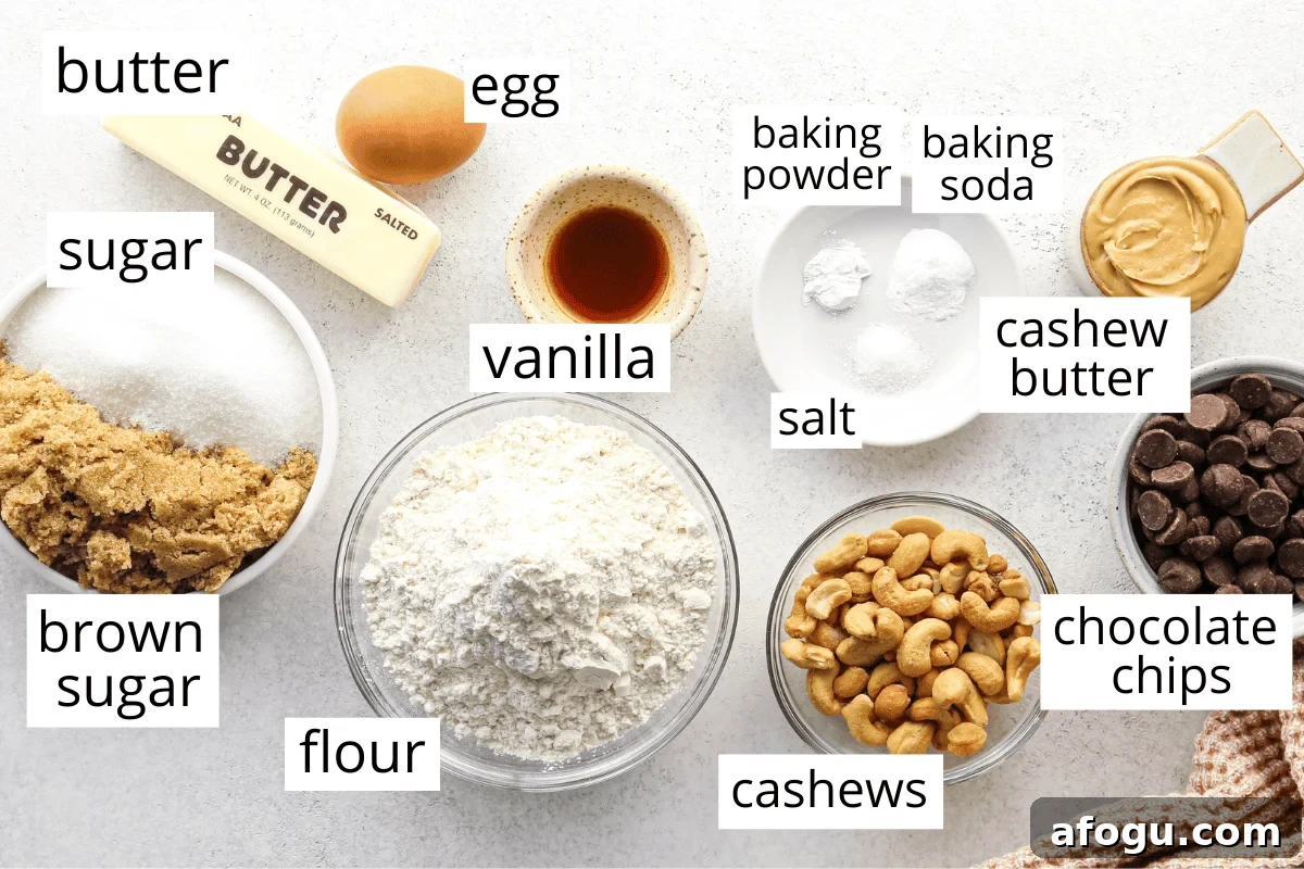 Chocolate Chip Cashew Cookies Recipe — Crunchy Homemade Treats 4 Overhead view of ingredients for chocolate chip cashew cookies arranged on a light countertop, including butter, egg, sugar, brown sugar, vanilla, flour, baking powder, baking soda, salt, cashew butter, cashews, and chocolate chips.