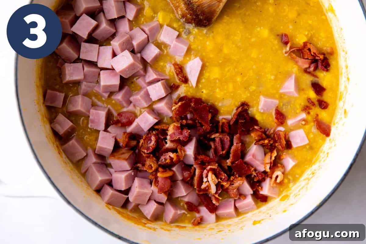 Diced ham and cooked bacon being added to corn chowder.