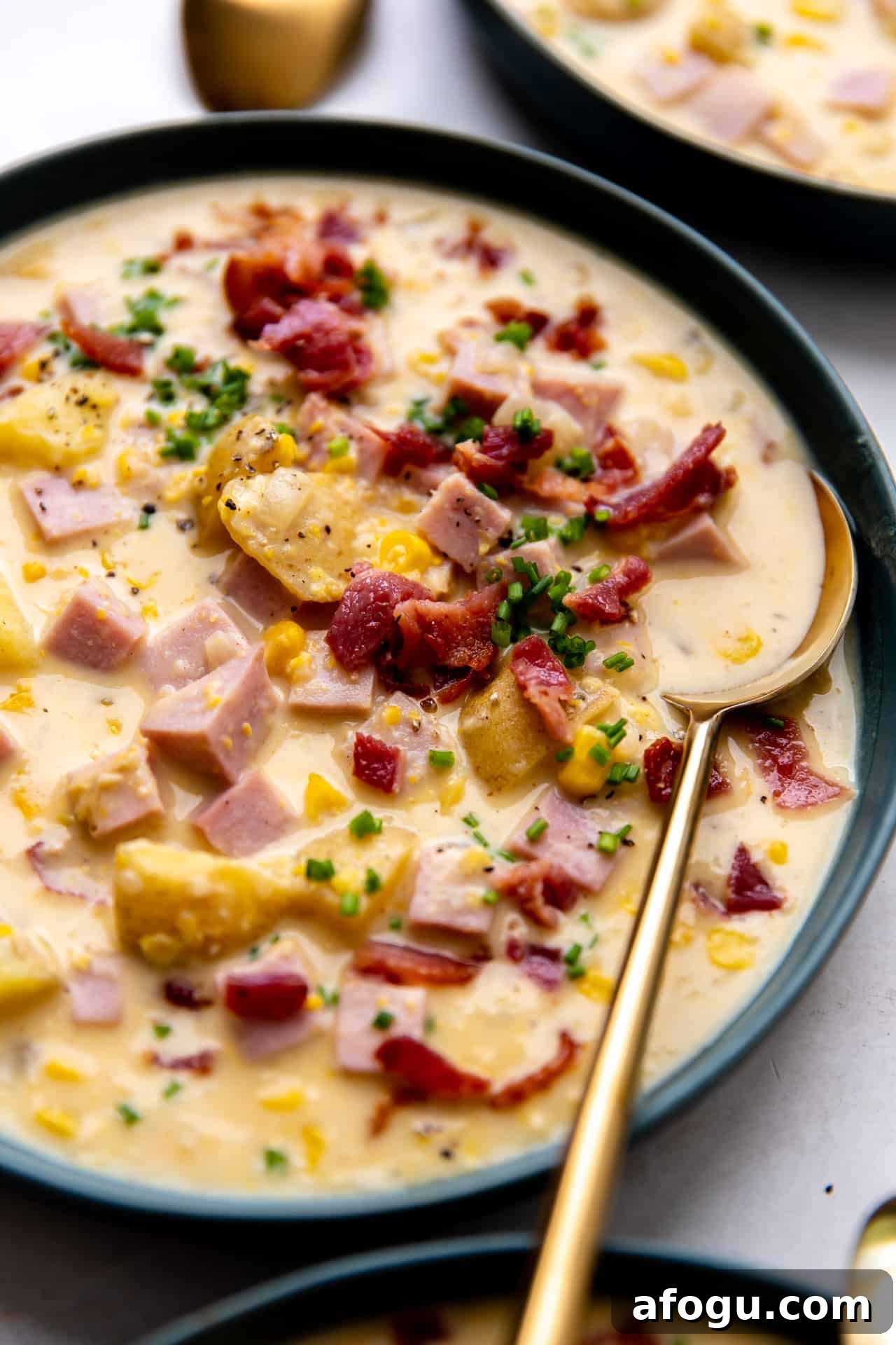 Up close view of a bowl of corn chowder topped with crisp bacon and fresh chives. 