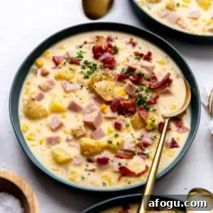 Bowl of corn chowder topped with crispy bacon and garnished with fresh chives.
