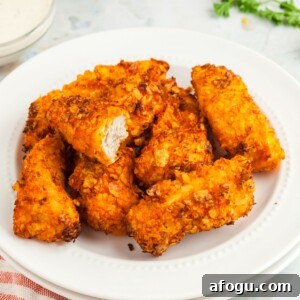Crispy Dorito-Crusted Air Fryer Chicken Recipe 10 Golden nacho cheese dorito crusted chicken tenders on a white plate