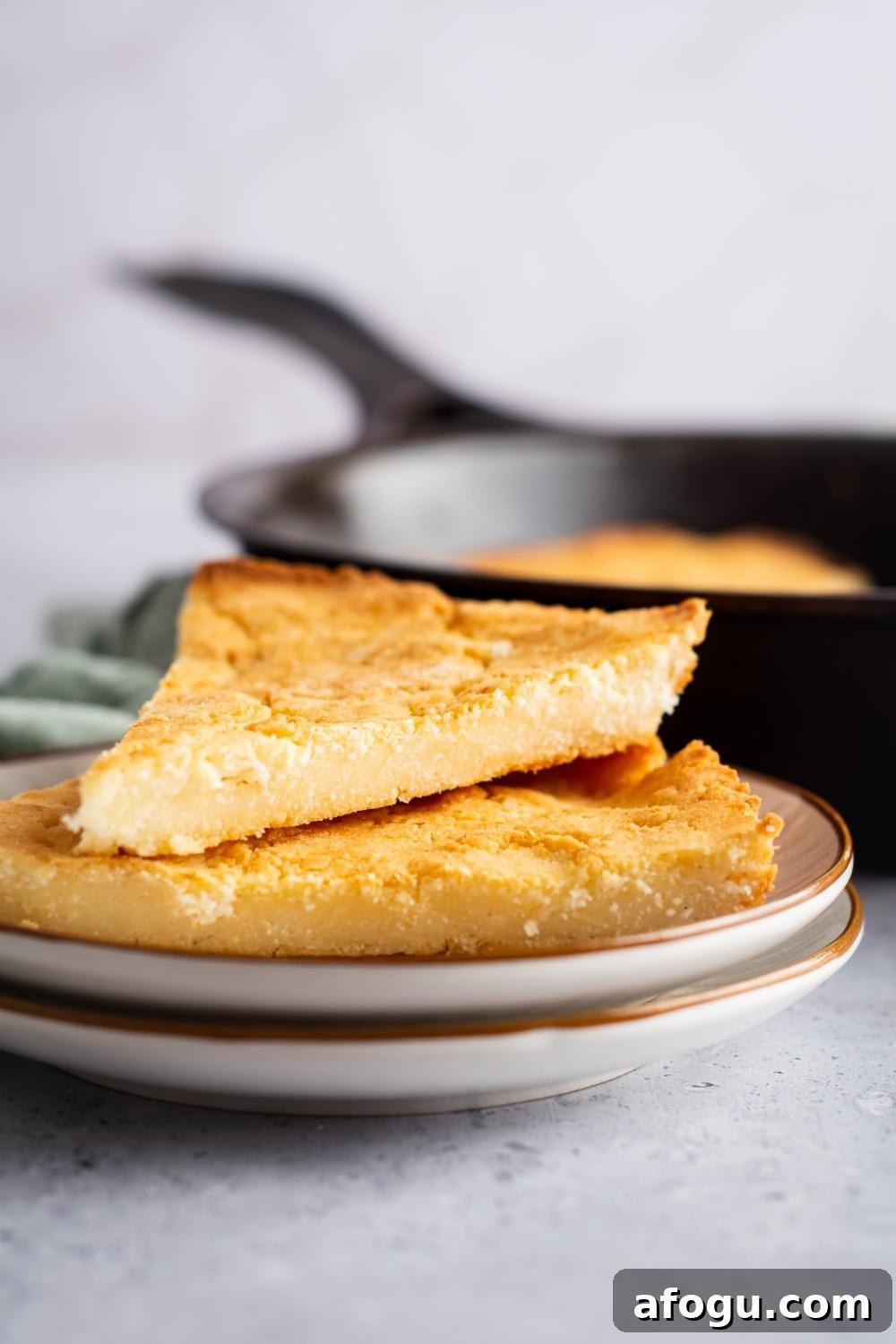 A white plate with two pieces of cornbread on it.