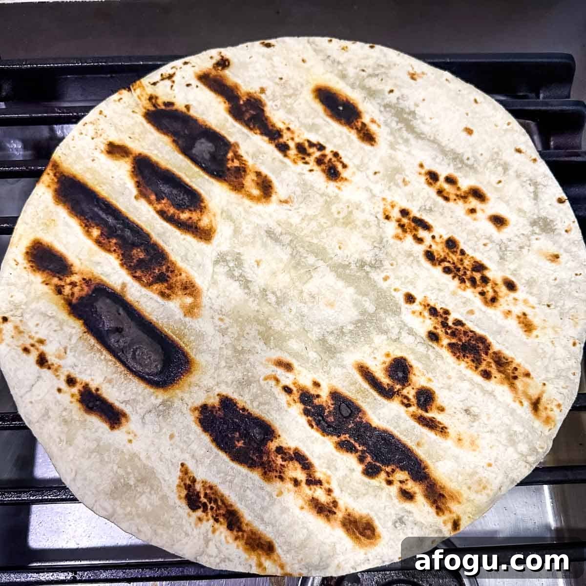Grilled tortilla on the grates of the stove.