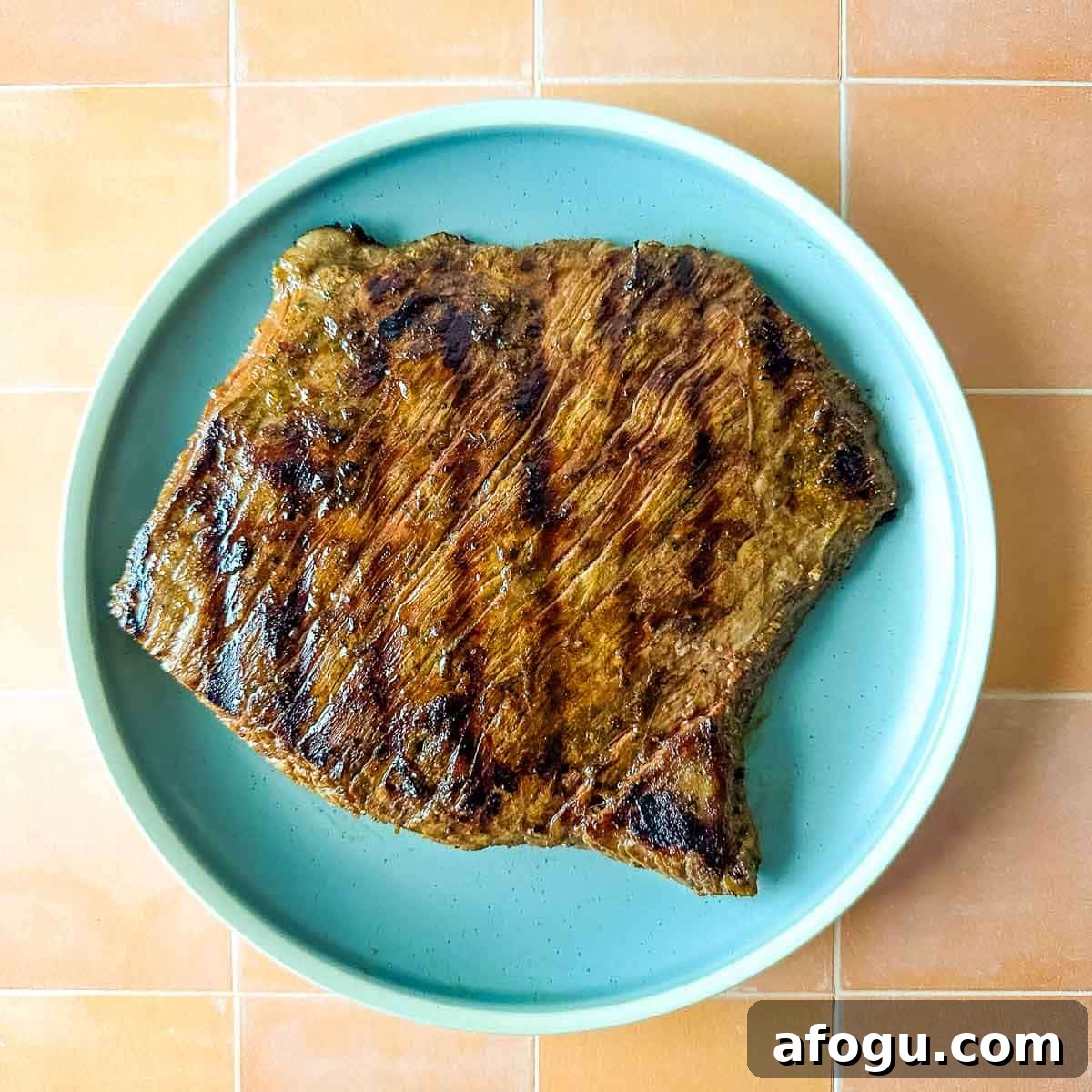 A grilled steak sits on a light blue plate.