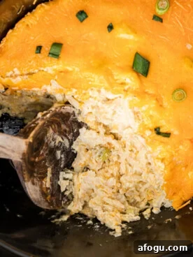 A large wooden spoon scooping out some slow cooker party potatoes.