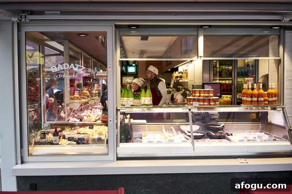 Top Vienna Markets: Where to Shop Local Food, Crafts & Gifts 9 Radatz butcher shop at Rochusmarkt in Vienna. Looking through a window toward a man in a white hat working at a meat counter. Cheeses and cold salads are displayed in the window.