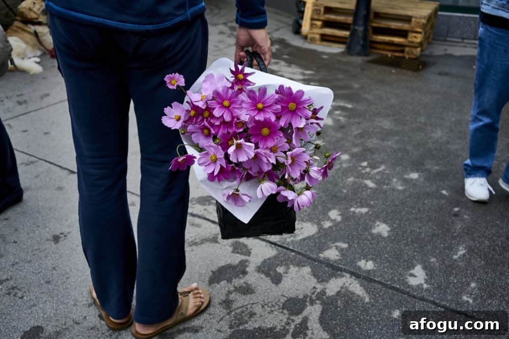 Top Vienna Markets: Where to Shop Local Food, Crafts & Gifts 10 A man wearing blue pants and tan flip flops shown from the waist down holds a basket of purple flowers at Rochusmarkt in Vienna.