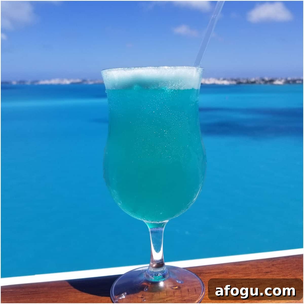 Blue Margarita on a wood rail with the ocean behind it