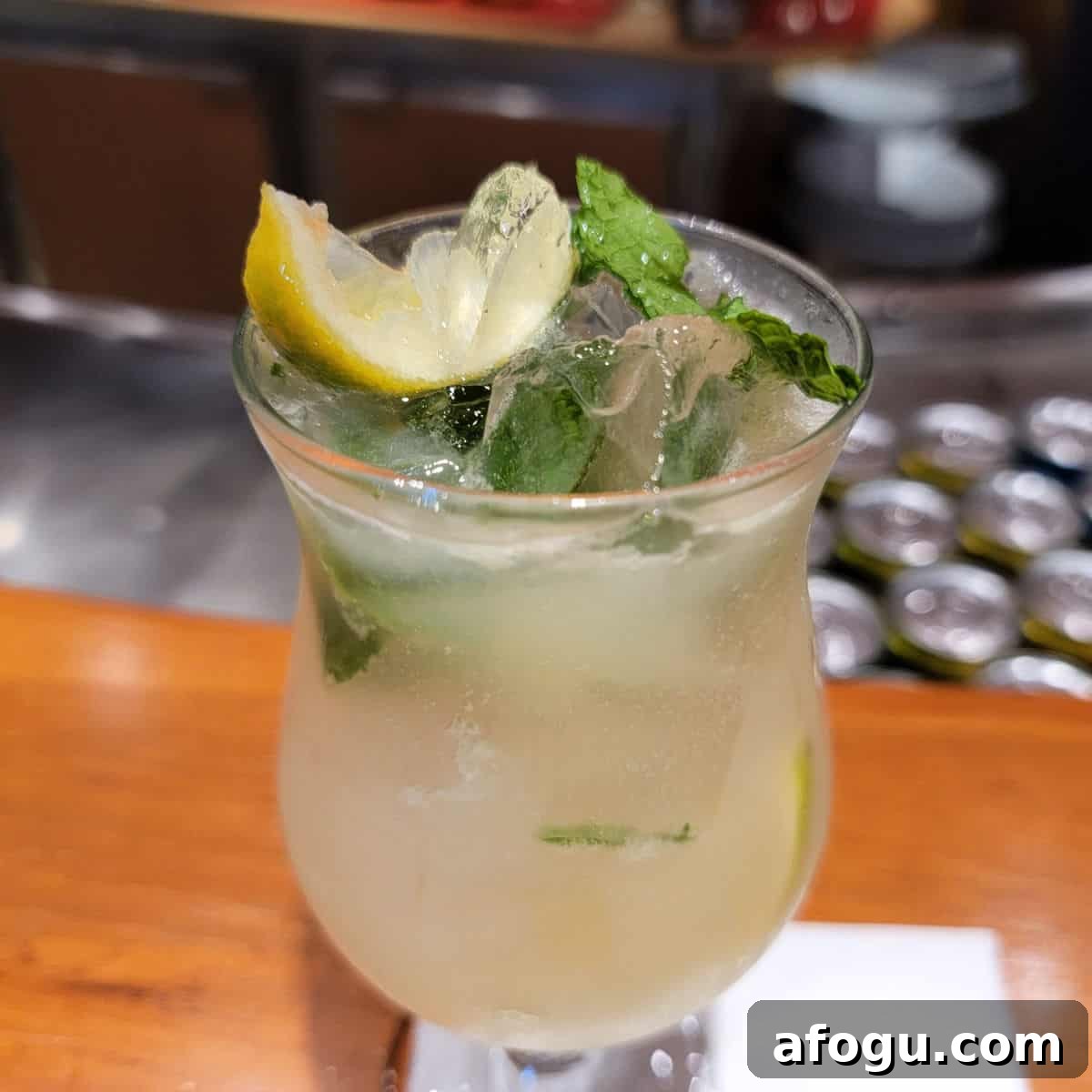 Ting Mojito in a hurricane glass with mint and lemon wedges