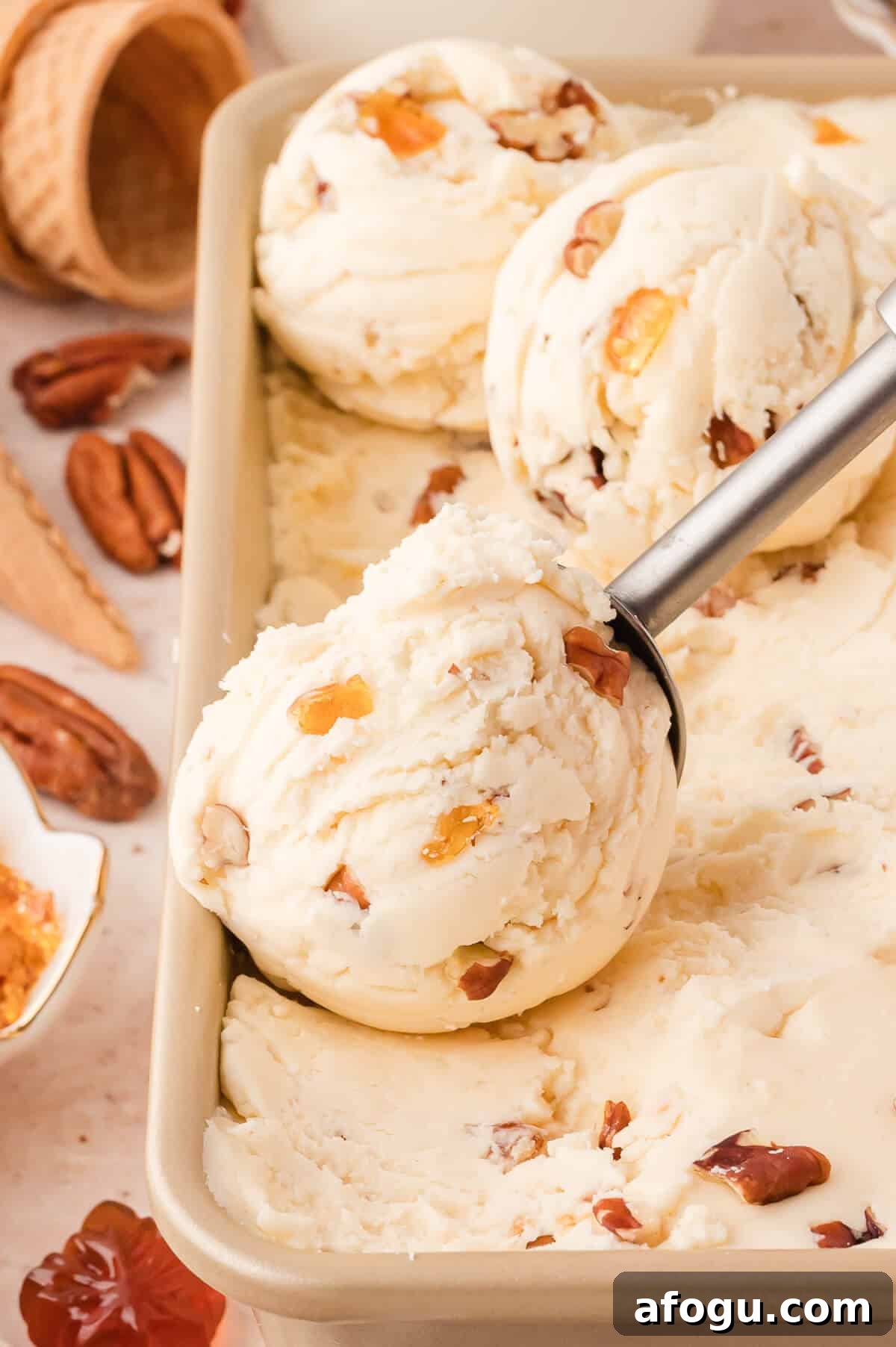 Maple pecan ice cream in a container with an ice cream scoop.