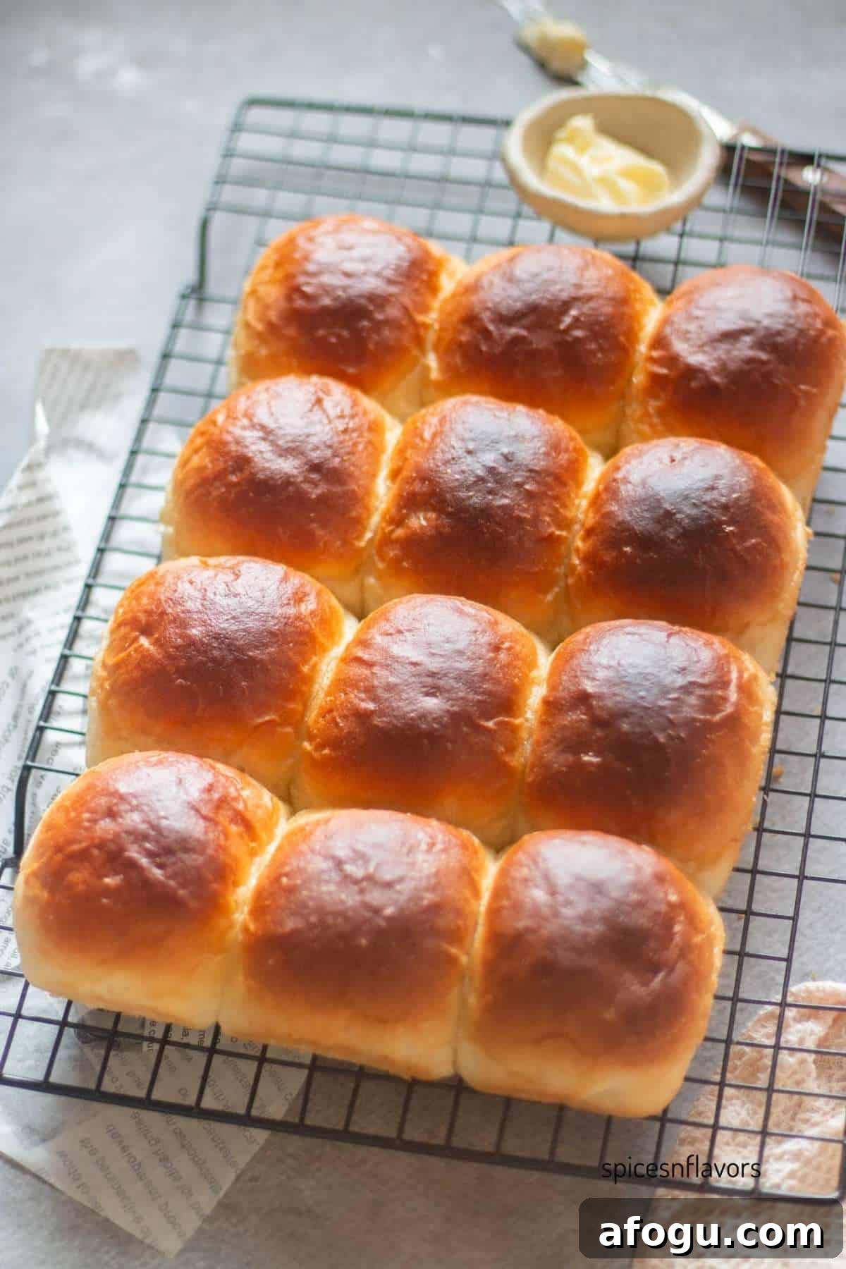 baked dinner rolls placed on a wire rack with butter bowl and knife on the side