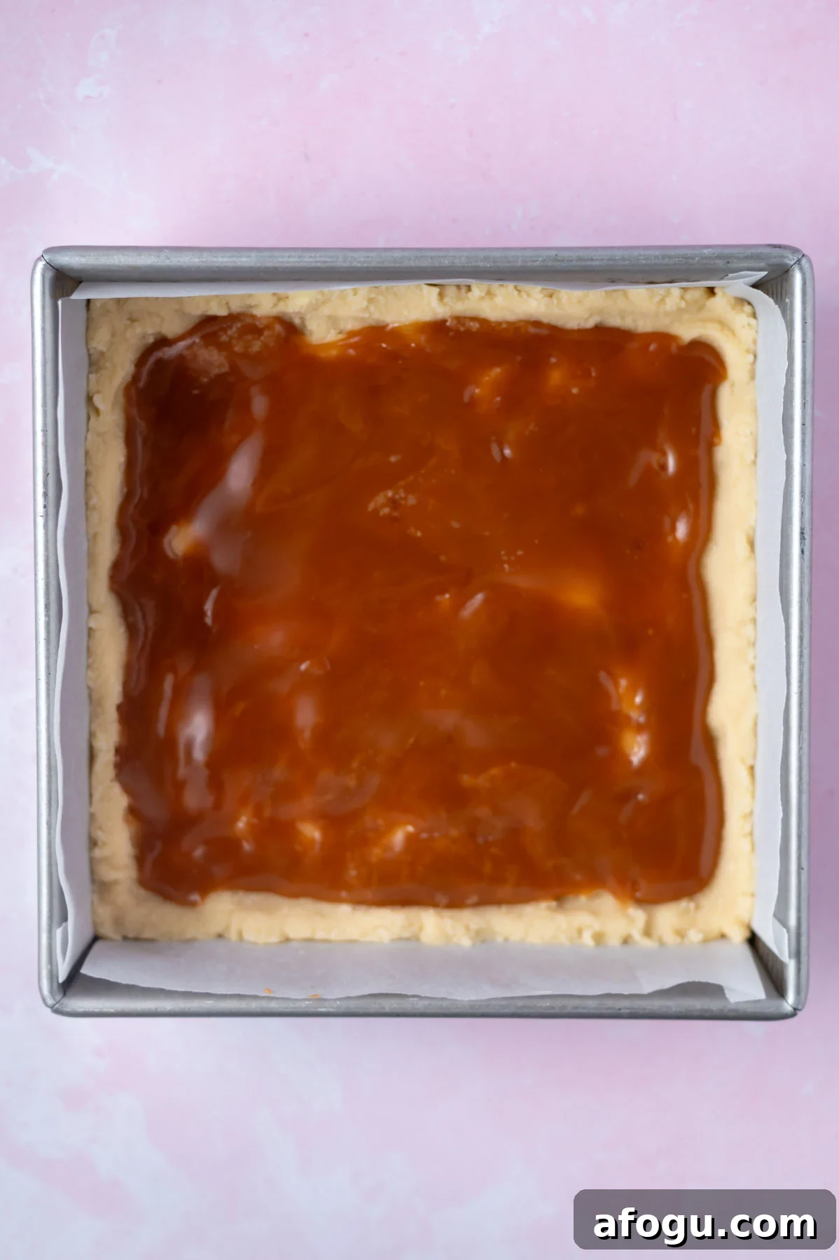 salted caramel sauce spread over shortbread in a baking pan
