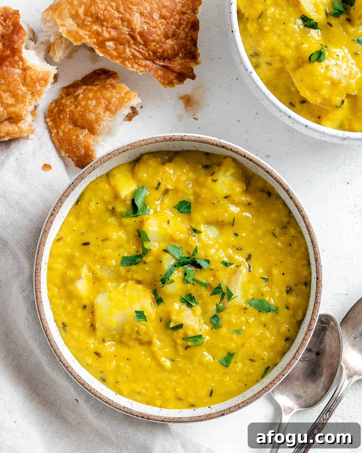 completed Lentil Potato Soup in a white bowl with ingredients in the background