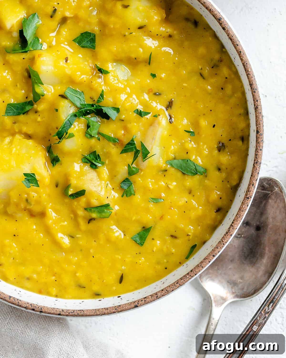 completed Lentil Potato Soup in a white bowl with ingredients in the background