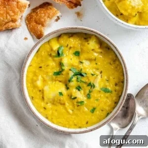 completed Lentil Potato Soup in a white bowl with ingredients in the background
