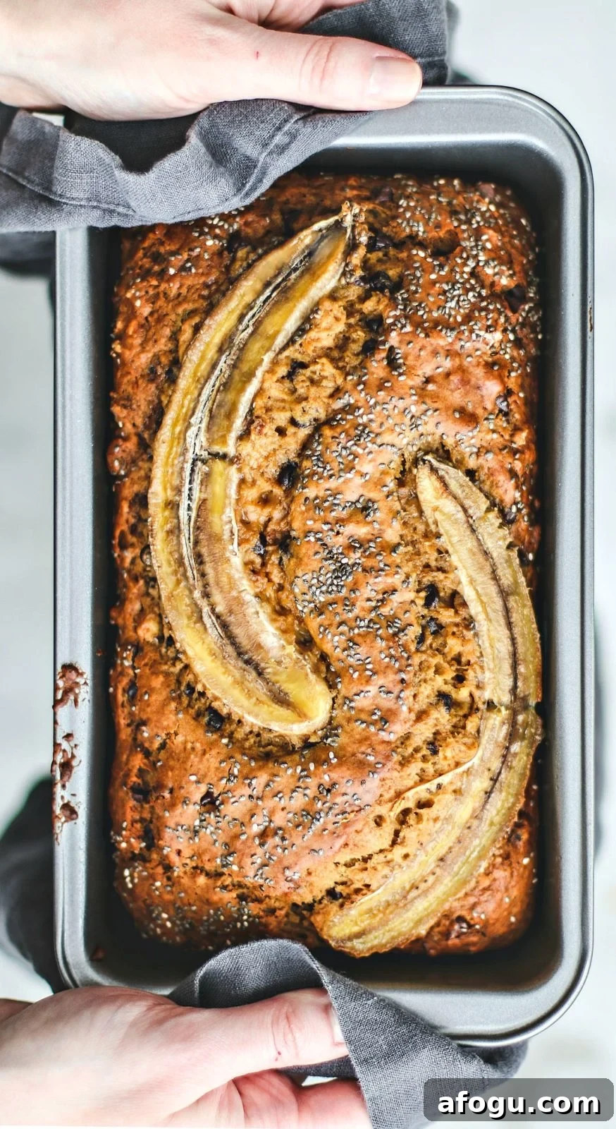 Walnut Chocolate Chip Banana Bread with Sour Cream Swirl 2 Hands holding up rustic banana bread in bread pan.