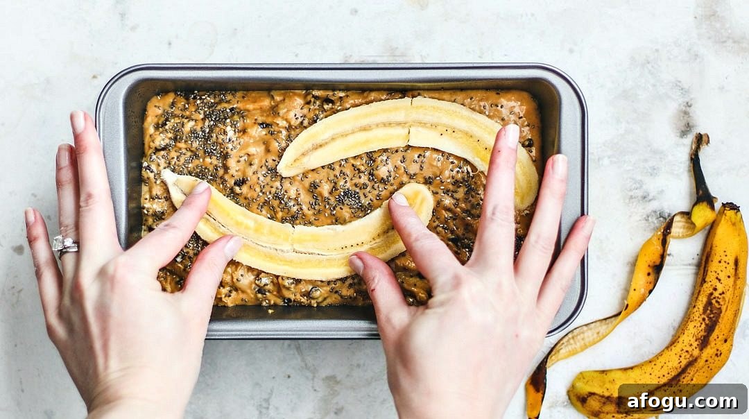 Walnut Chocolate Chip Banana Bread with Sour Cream Swirl 6 Hands pressing banana halves into uncooked banana bread loaf.
