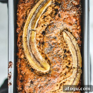 Hands holding up rustic banana bread in bread pan.