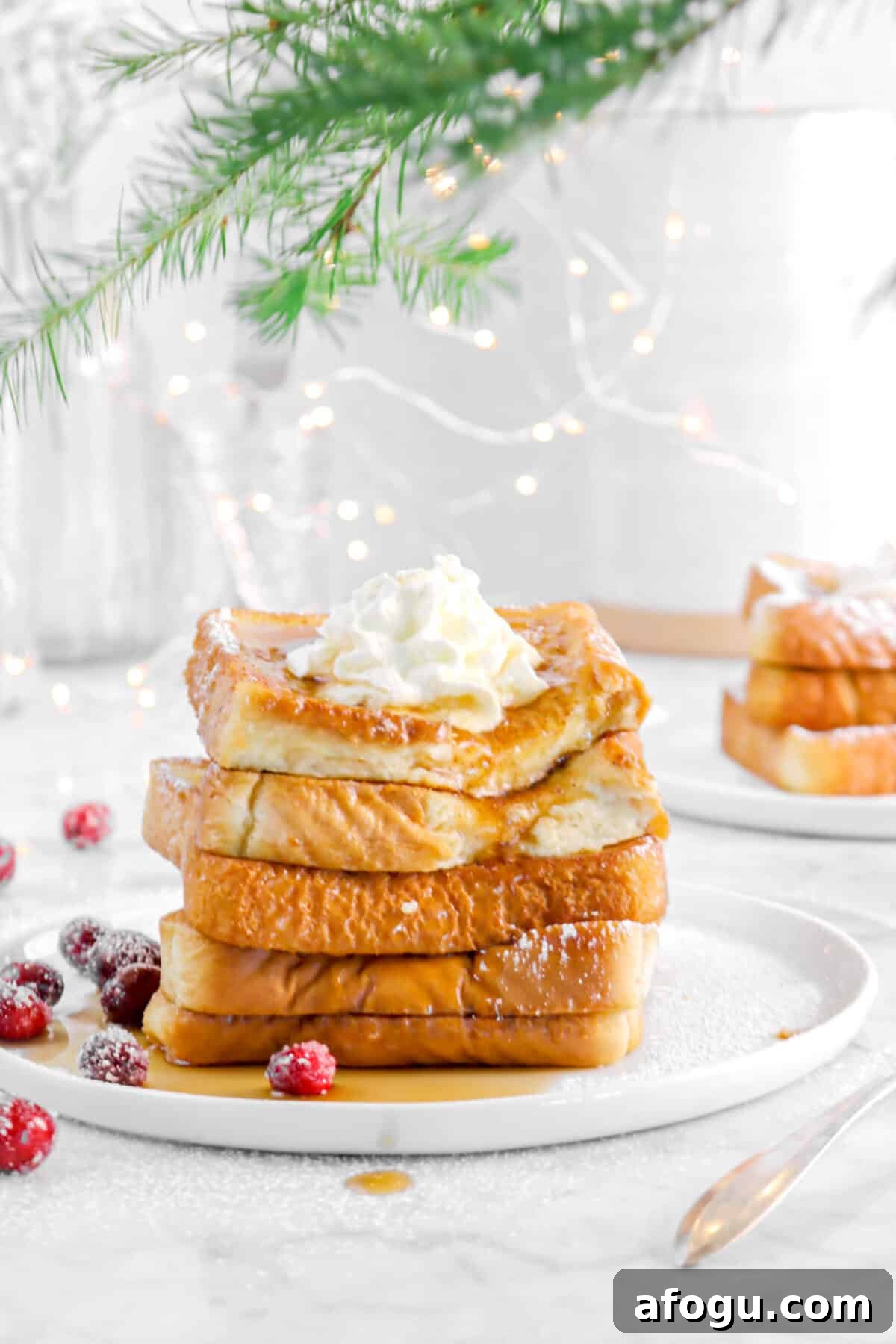Eggnog French Toast Recipe: Festive Holiday Brunch Idea 6 bite taken out of french toast with fairy lights, cranberries, and greenery