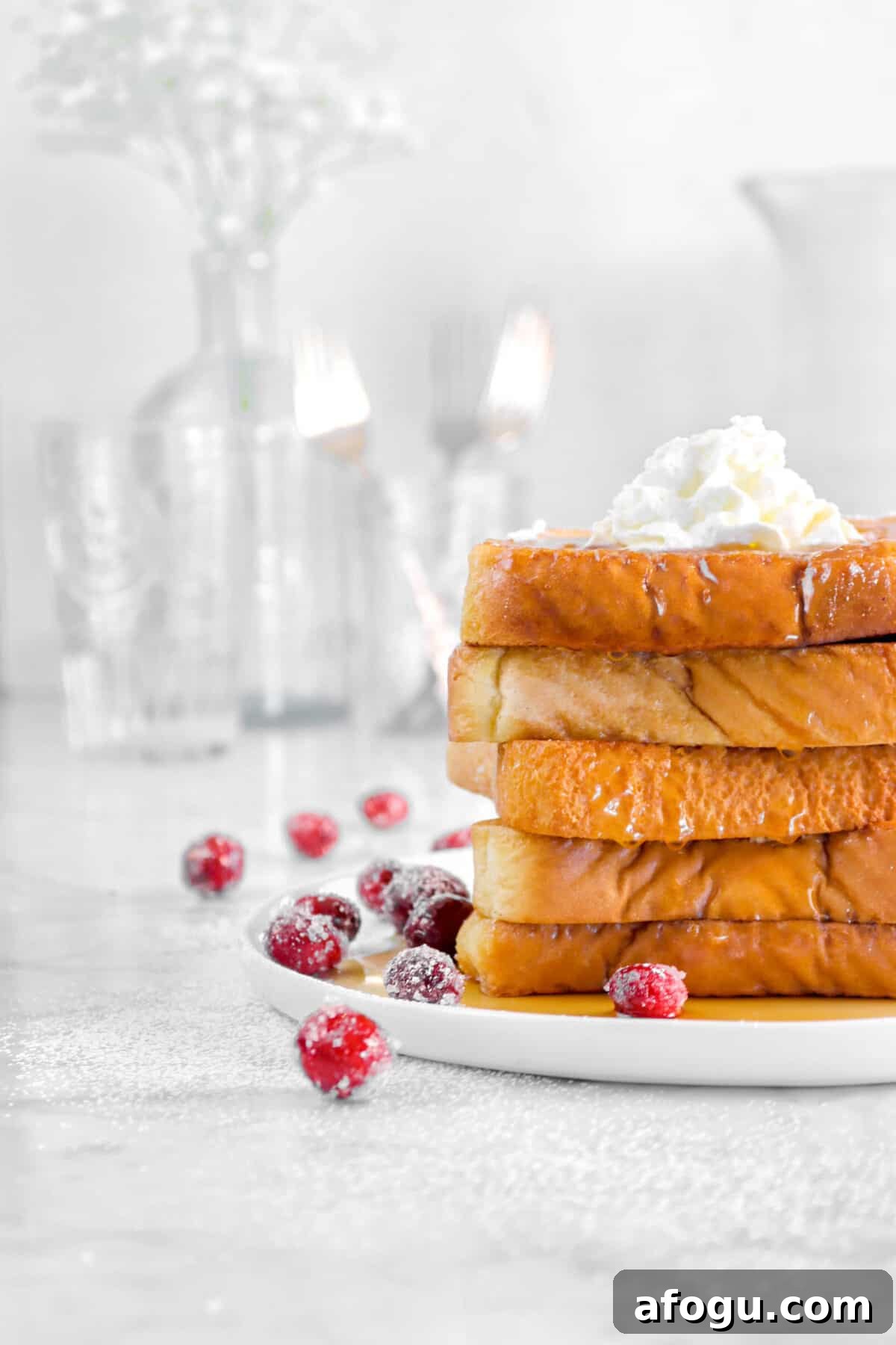 Eggnog French Toast Recipe: Festive Holiday Brunch Idea 8 french toast on a plate with glassed behind and cranberries