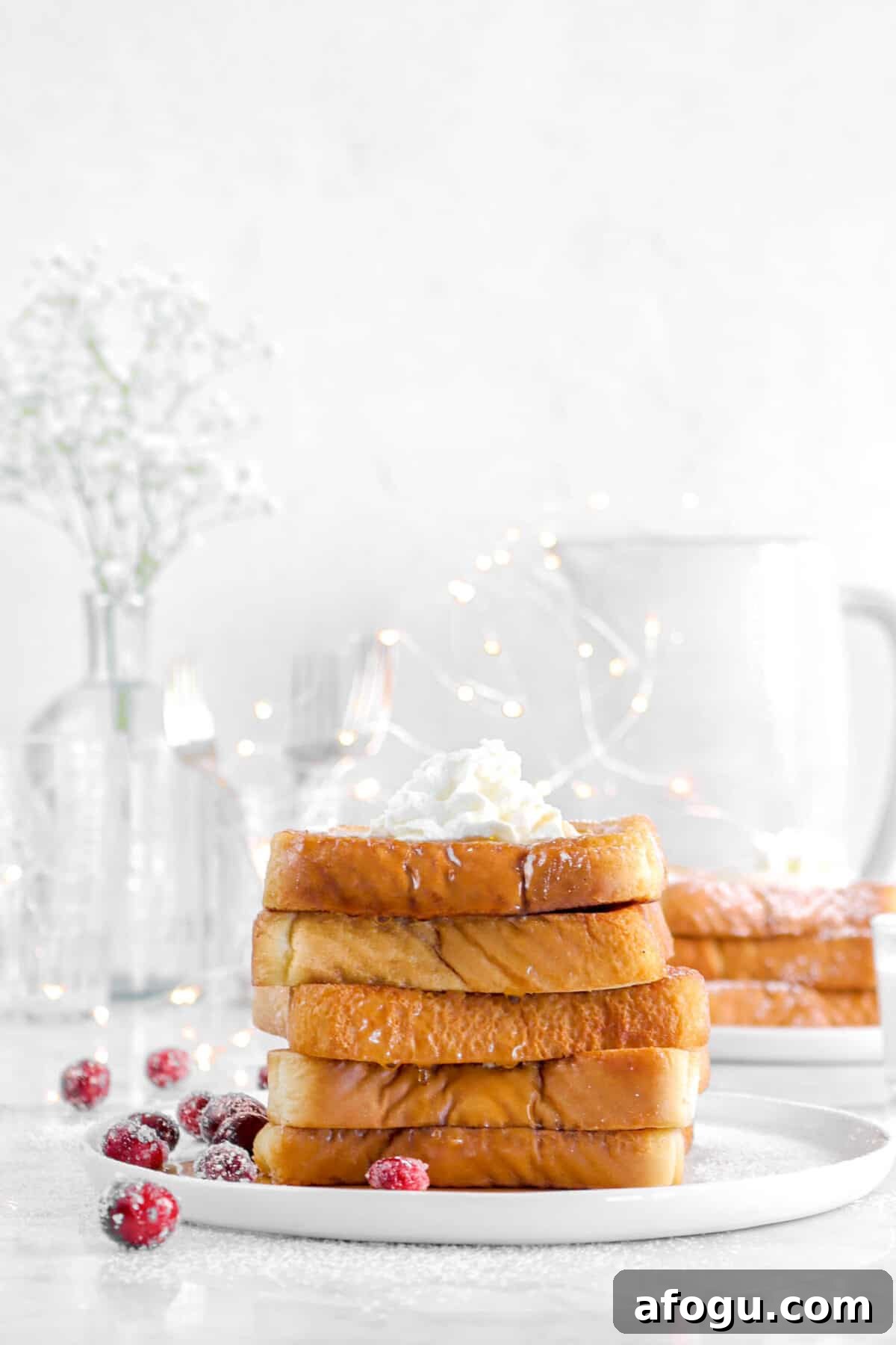 Eggnog French Toast Recipe: Festive Holiday Brunch Idea 3 stacked french toast with fairy lights, glasses, and flowers behind