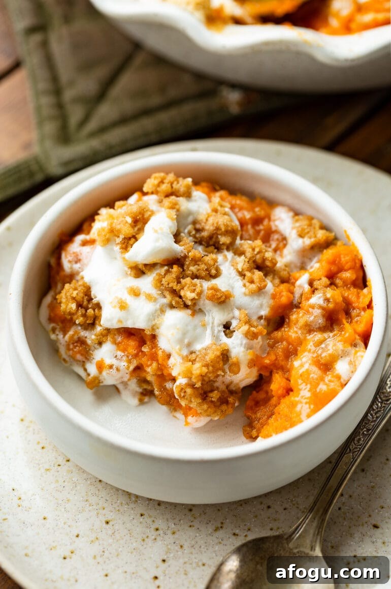 a photo of a serving of orange vegetable casserole in a small dish with a spoon next to it