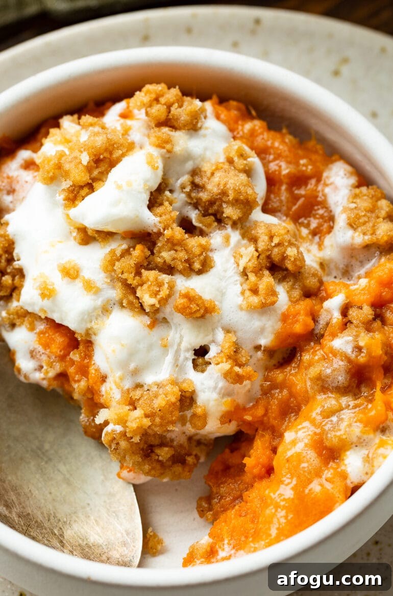a photo of a serving of sweet potato casserole topped with melted marshmallows and brown sugar streusel in a small bowl 