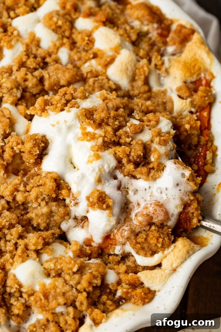 a photo of a baking dish full of baked sweet potato casserole topped with melted marshmallows and a brown sugar streusel.