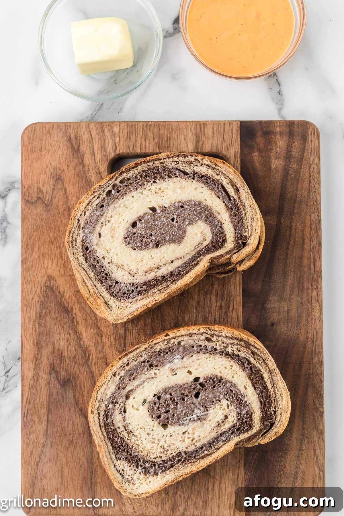 Rye bread slices stacked on a cutting board with a bowl of butter and Thousand Island dressing on the side