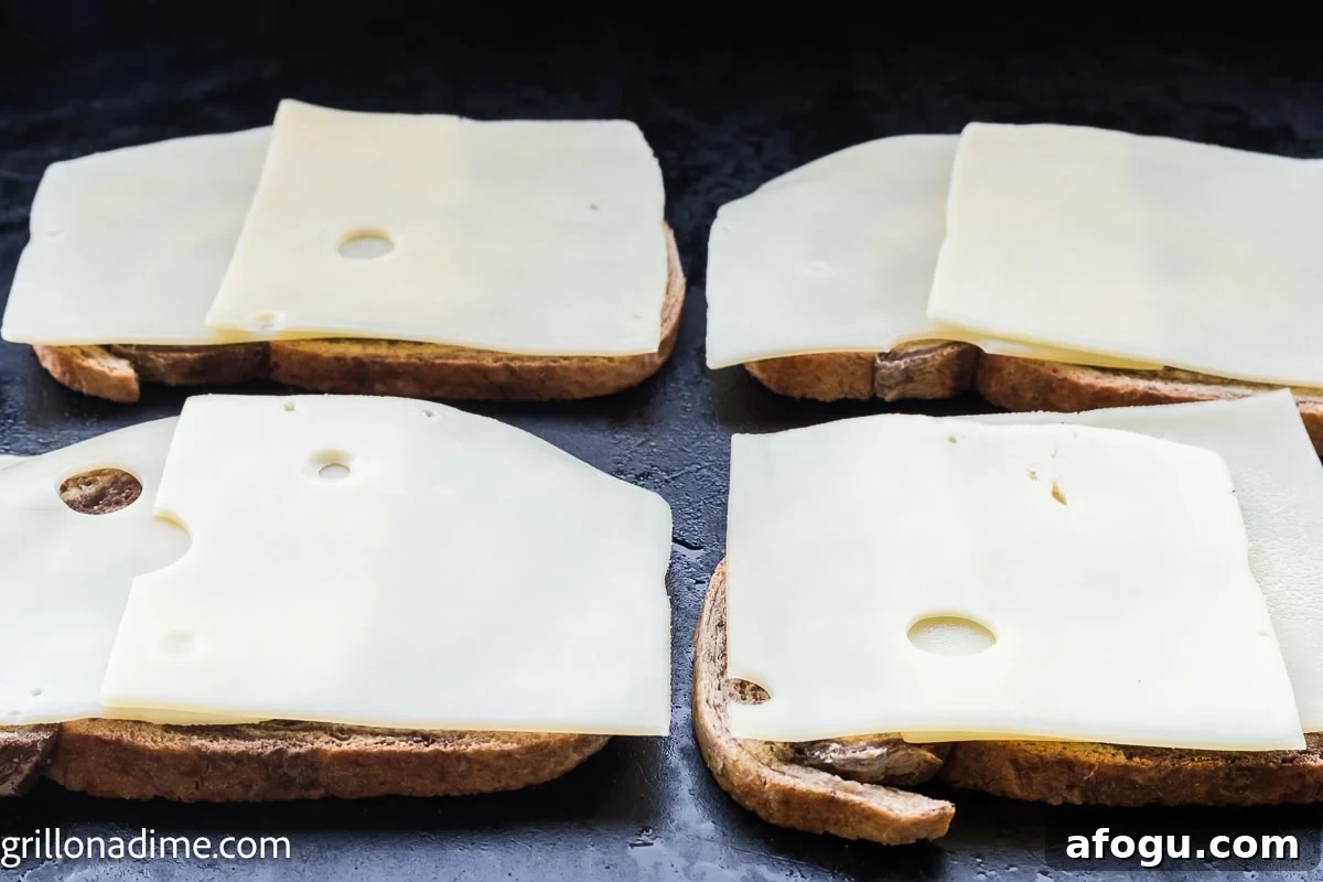 Rye bread on the griddle topped with swiss cheese slices