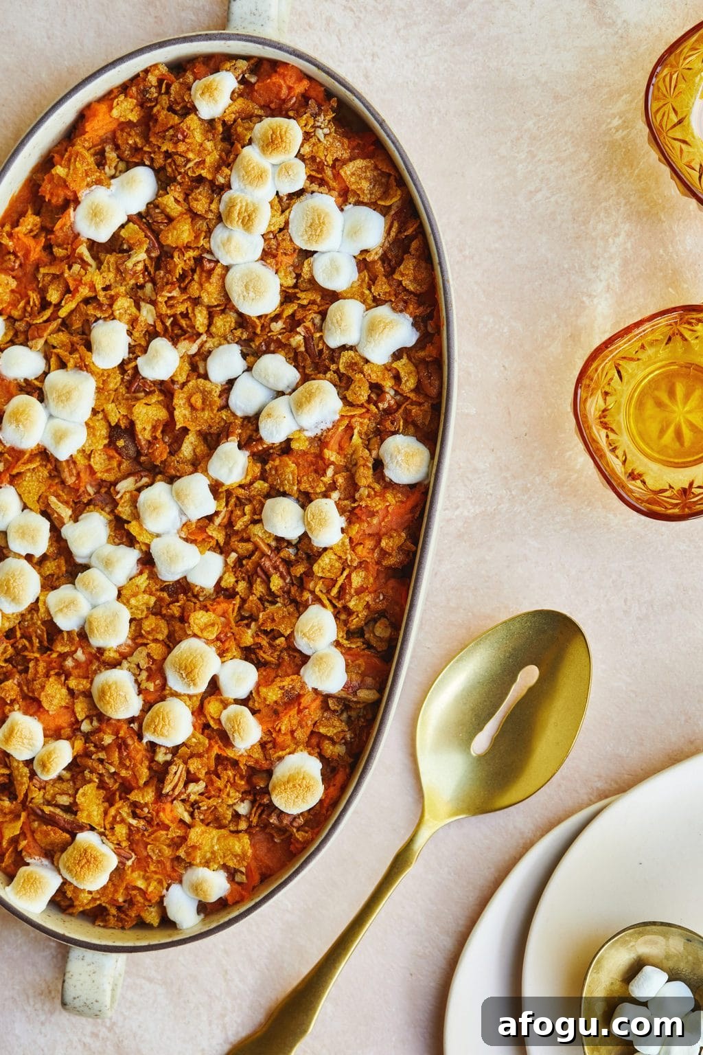 Platter of mashed sweet potatoes with marshmallows and a golden spoon next to the dish. 