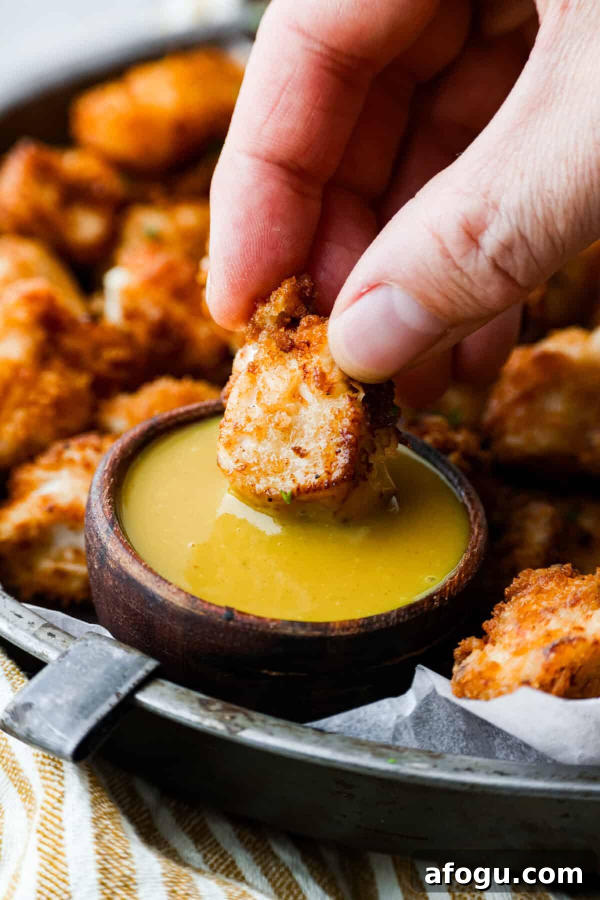 A copycat Chick-fil-A nugget being dipped in homemade chick-fil-a sauce. 