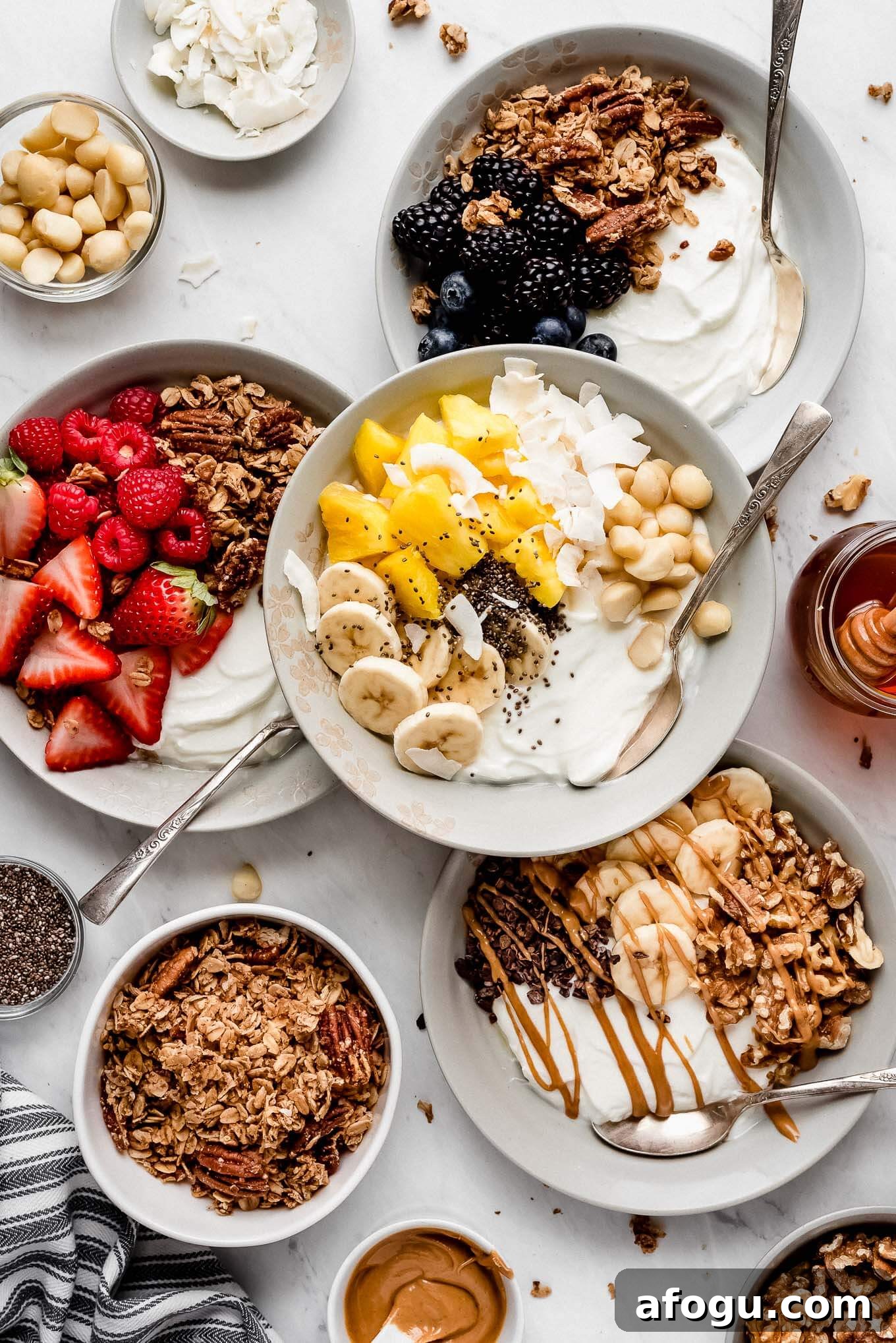 Don't get hangry! Enjoy one of these 4 wholesome Greek Yogurt Bowls made with FAGE Total 0% Plain that nourish your body and keep you feeling full. 4 Greek Yogurt Bowls full of fruits, granola, seeds, and nuts as well as little bowls of nuts, seeds, and granola surrounding.
