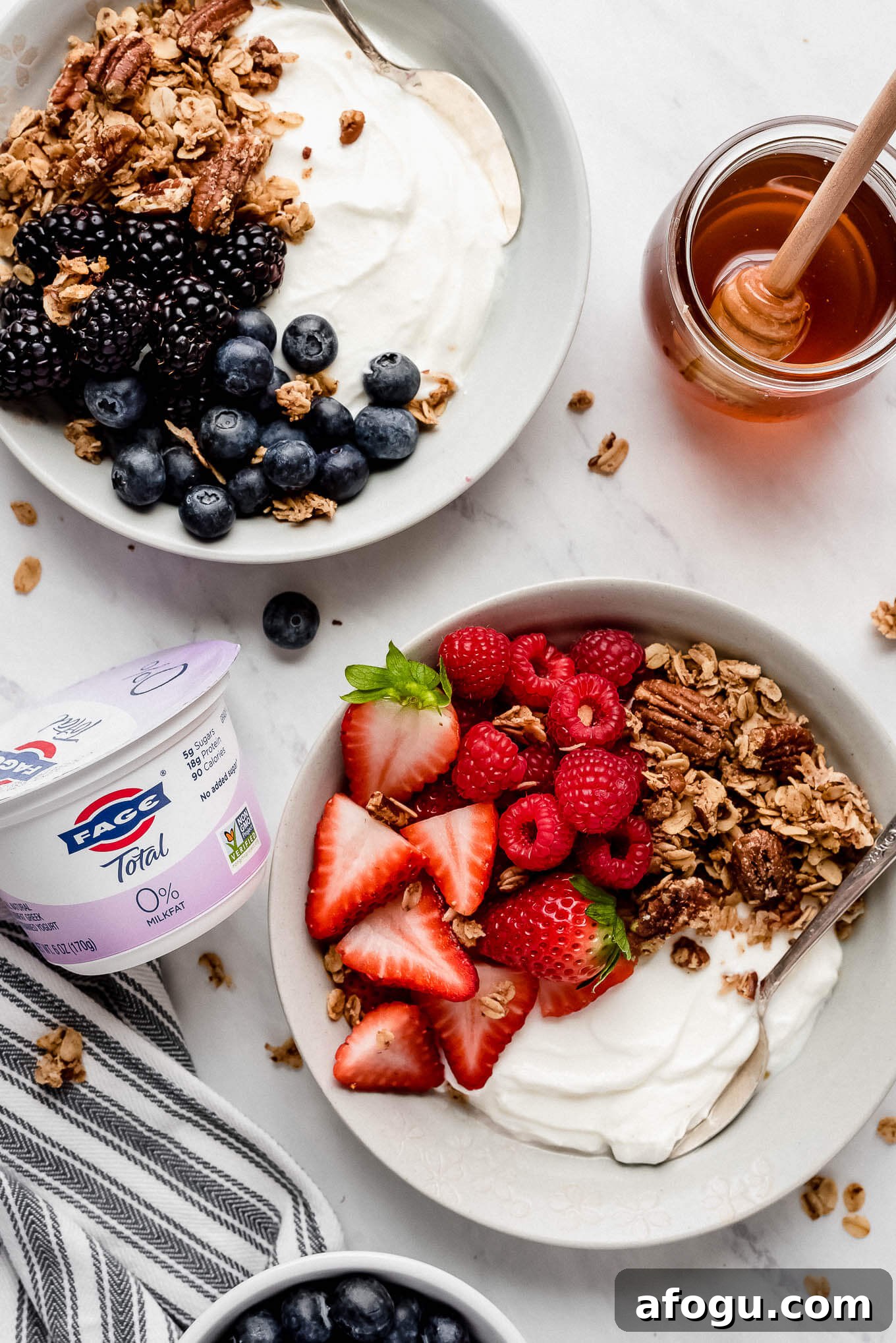 Berry yogurt bowls. A yogurt bowl with black and blueberries and granola and a yogurt bowl with strawberries, raspberries, and granola.