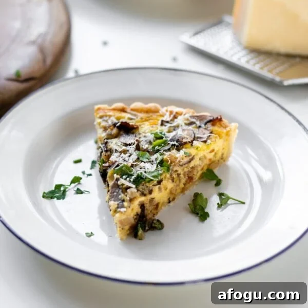 Breakfast quiche topped with parsley and Parmesan cheese sitting on white plate with extra cheese and bread board in background all on white surface