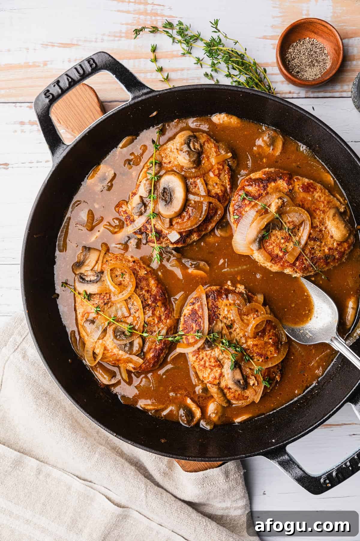 A skillet with turkey patties in a brown gravy.