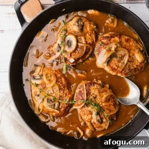 Turkey salisbury steak in a skillet with mushroom gravy.
