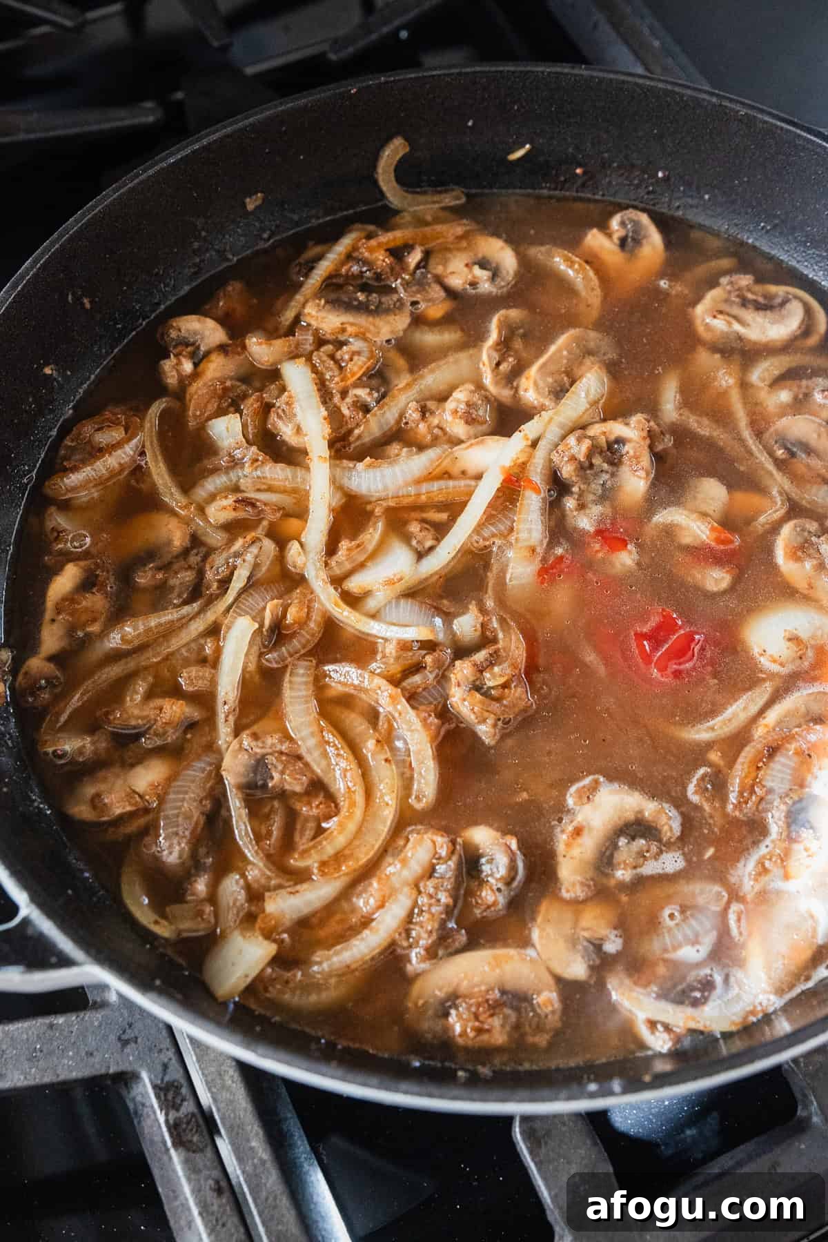 Broth and ketchup added to a skillet to make gravy.