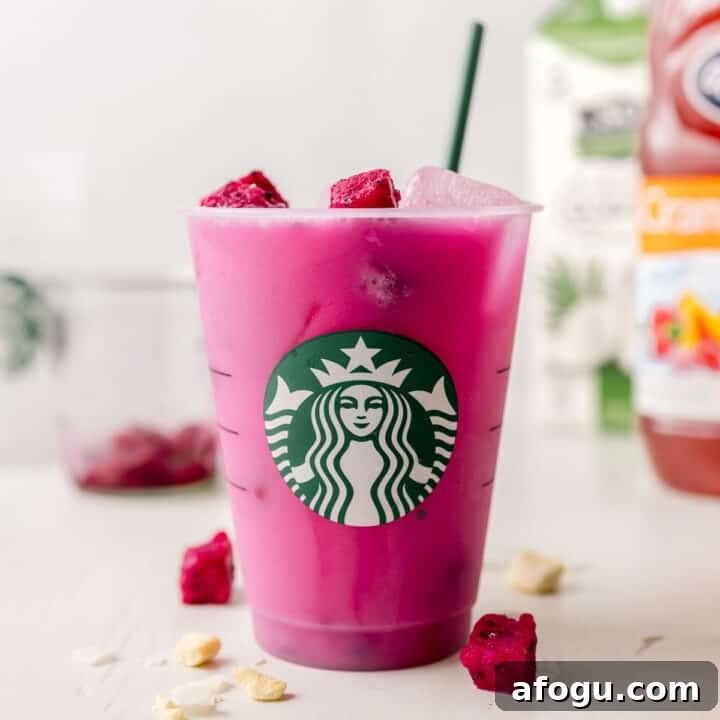 Starbucks dragon drink in a Starbucks cup with green straw and dragon fruit pieces.