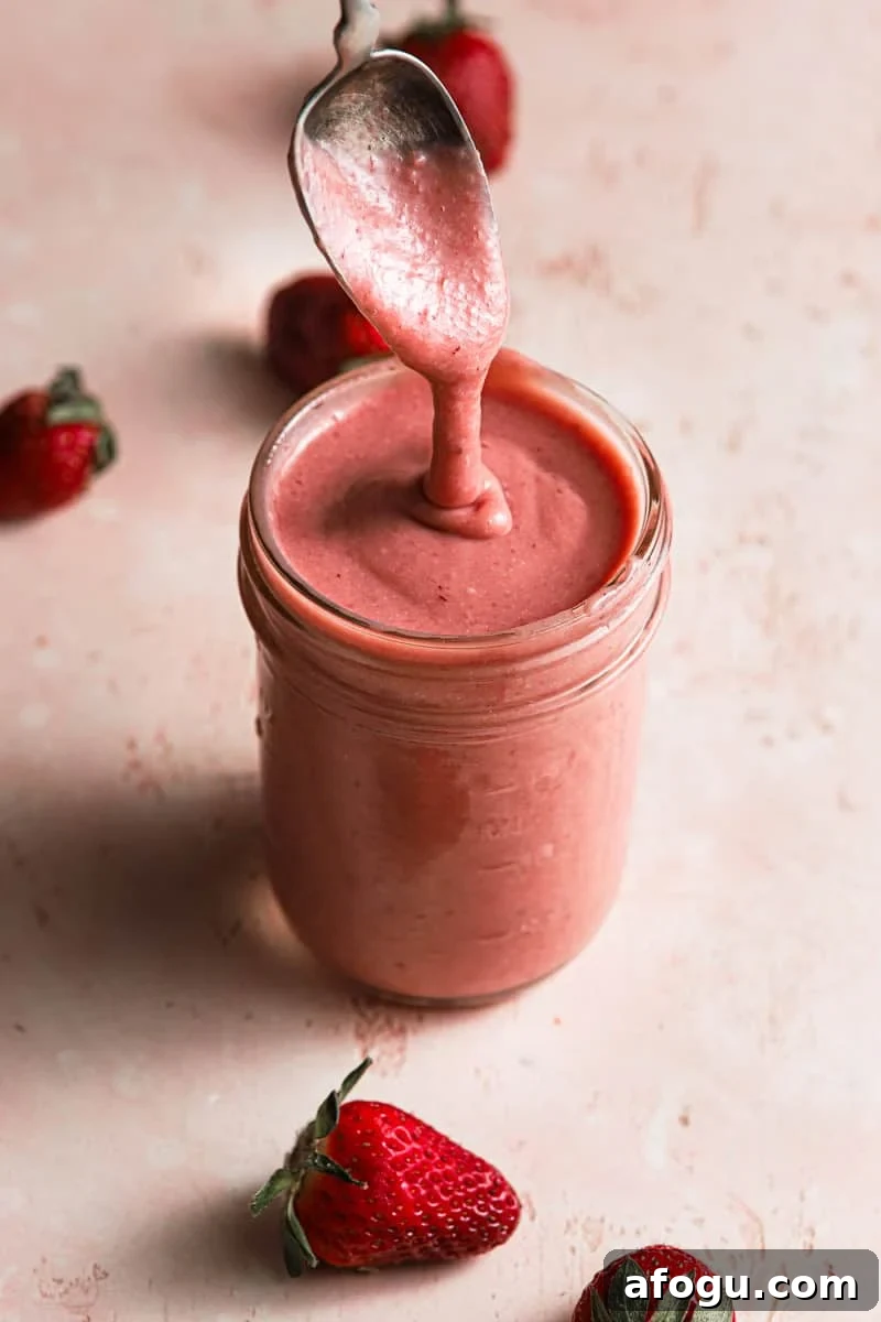 A mason jar full of pink curd and a spoon coming out of it.