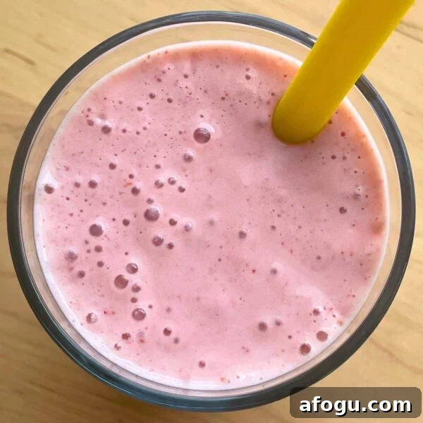 A close-up of a strawberry banana smoothie with Greek yogurt with a yellow straw.