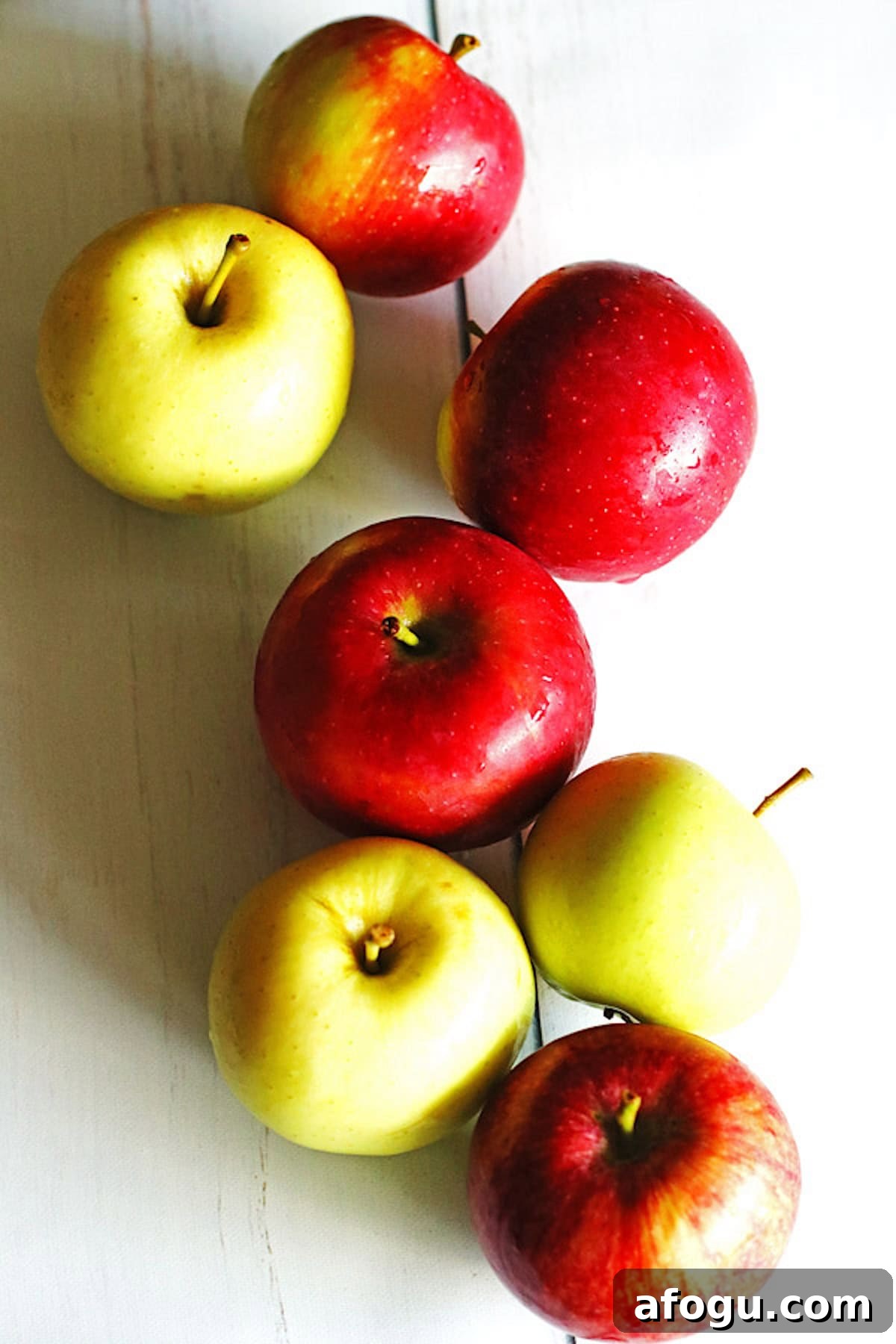 Red and green apples on a white table
