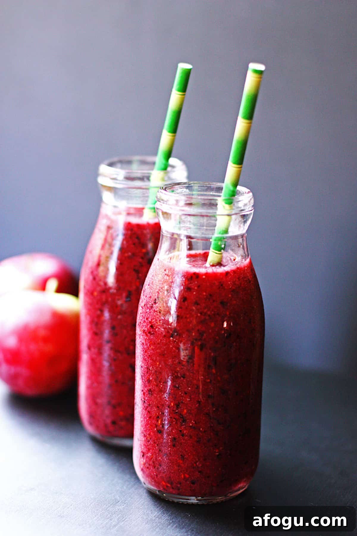 Two jars of apple berry smoothie with green straws.